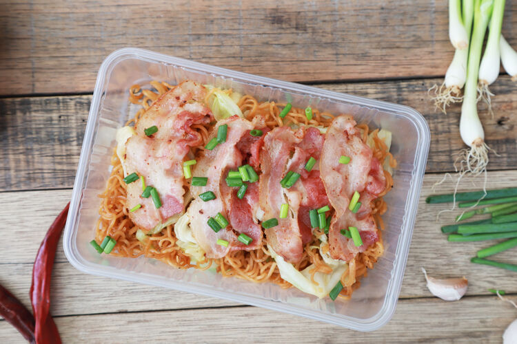 亚洲菜桌上有猪肉筷子炒方便面 塑料盒装快餐盘子猪肉晚餐