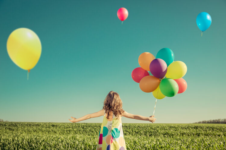 想法快乐的孩子玩着五颜六色的玩具气球户外微笑孩子们在蓝天映衬下的绿色春田里玩得很开心背景.自由概念明亮户外美丽