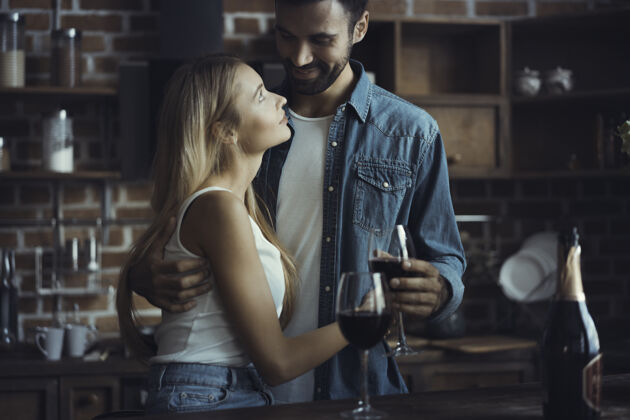 一起美丽的年轻夫妇在家里的厨房边喝酒边微笑酒健康薯条