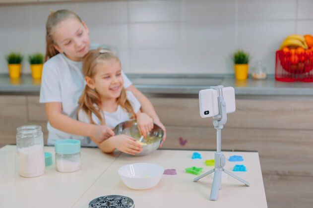 食物两位姐妹博客作者在厨房做饭 并用智能手机拍摄烹饪视频房间关系房子