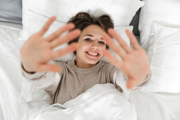 室内一个微笑的年轻女孩在床上放松的俯视图放松漂亮唤醒