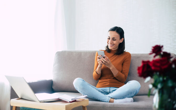 在线快乐兴奋的美女 沙发上放着智能手机连接现代沙发