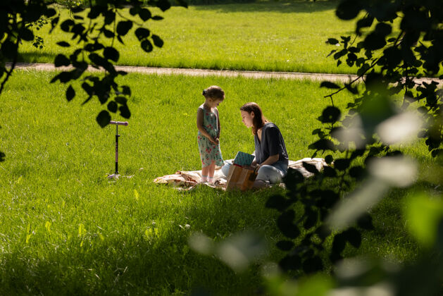 快乐莫斯科\/俄罗斯-2020年6月：母女俩坐在草地上看书花园玩耍女人