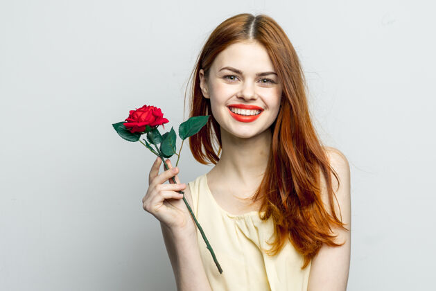 浪漫微笑的女人手里捧着玫瑰花迷人的红唇迷人的样子孤立头发白天肖像