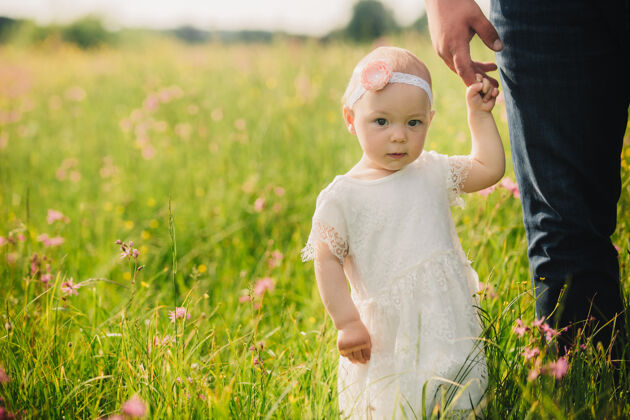 幼儿园微笑着的白裙小女孩 带着野花走在田野里童年户外乐趣