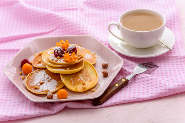 面包房自制的薄煎饼配上覆盆子 酸浆 粉糖和粉色餐巾 再配上一杯茶或咖啡毛巾蜂蜜营养
