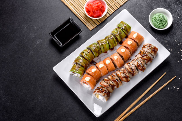 沙司新鲜美味的寿司卷 以龙的形式摆放着 上面放着姜和姜日本芥末美食健康传统酱油
