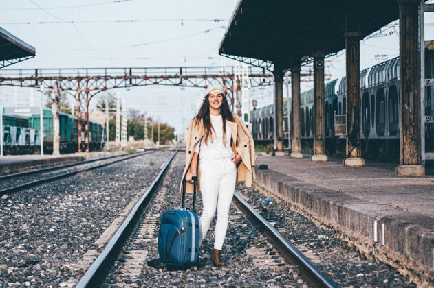运输一个穿着贝雷帽和米色夹克的女人在火车站等火车离开漂亮距离