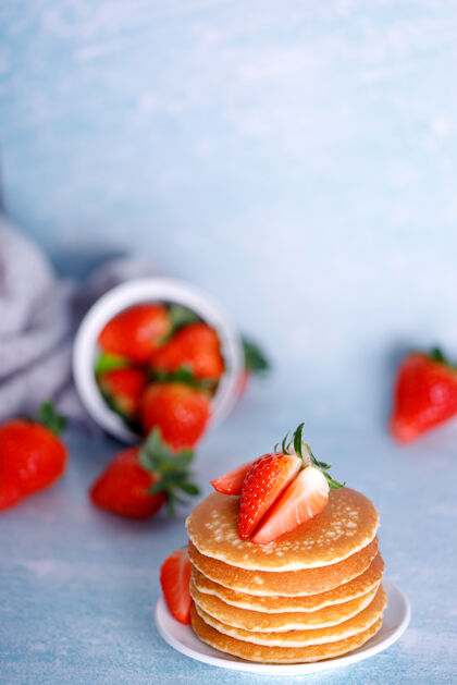 水果美味的美国薄饼 白色盘子上有草莓 蓝色背景面包房小吃烘焙