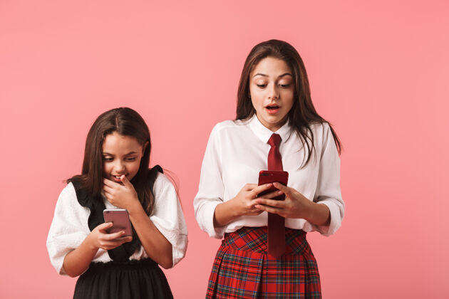 爱身着校服的乐观女孩一边用手机 一边孤立地站在红墙外的画像乐观积极课程