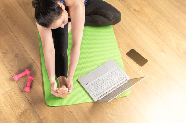 笔记本电脑在线笔记本瑜伽之家俯视图的妇女练习瑜伽垫瑜伽与笔记本电脑中年妇女正在家里通过视频训练冥想和放松教练护理练习