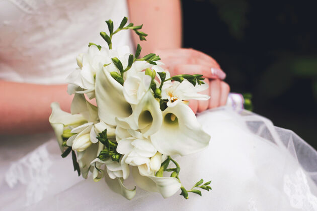 叶一位穿着白色婚纱的新娘手持一束白色马蹄莲的婚礼花束新娘仪式植物