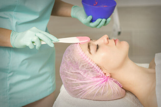 美容院在美容院的女人脸上用手敷海藻酸钠面膜化妆品女人应用