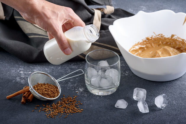 甜点特写制作达尔戈纳咖啡的过程 灰色厨房餐桌上的韩式饮料 手把牛奶倒进冰杯韩式准备自制