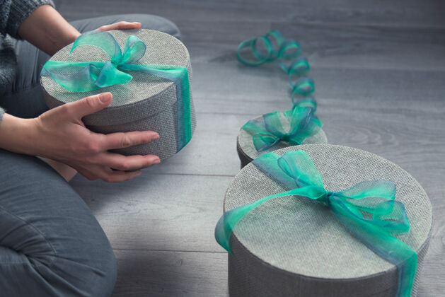 礼盒女人用灰色的圆盒子和绿色的丝带包装礼物礼物手工制作包