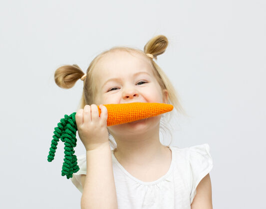 一快乐的小女孩手里拿着一个针织衫胡萝卜概念健康食品饭蔬菜小