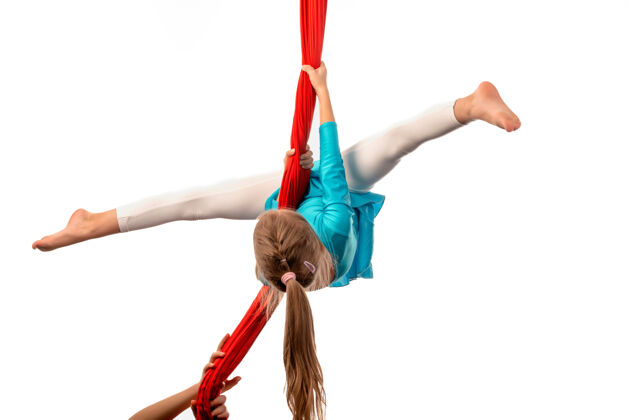健身房小杂技女孩在空中做劈叉手拿着一条白色的红丝带平衡人类竞技场