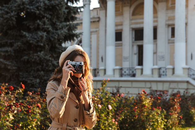 拍摄可爱的年轻女子穿着外套走在户外 用相机拍照数码成人户外