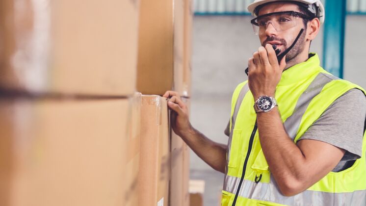 施工专业货运工人通过便携式无线电联系另一名工人维护交付阿拉伯语