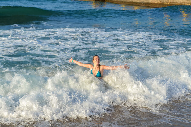 年轻女子一个年轻女孩在海浪中沐浴海岸海浪休闲
