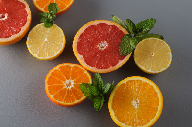 食品新鲜柑橘和薄荷切成两半背景多汁葡萄柚 橘子 柠檬 橙子 柑橘果汁配料 食品背景素食灰色新鲜