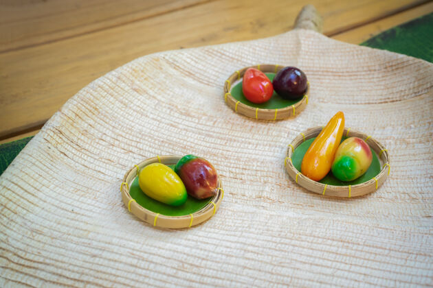 手工制作水果形状的绿豆-kanomlookchoup 泰国甜葡萄酒-柳条板上的现代美味五颜六色自制