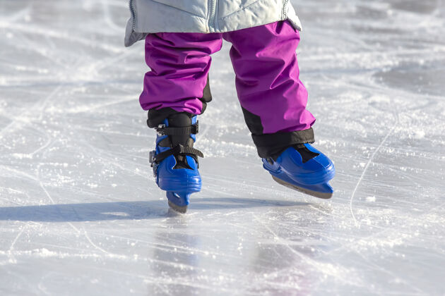 溜冰在溜冰场上滑冰的女孩的腿爱好和休闲冬季运动雪骑行运动