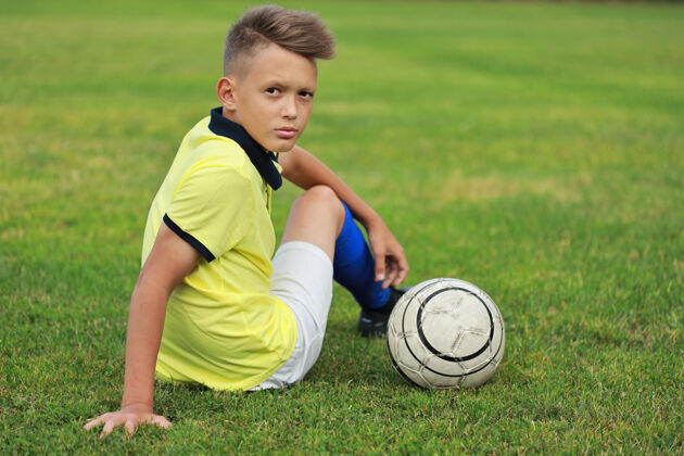 足球帅哥足球运动员坐在足球场上孩子游戏足球