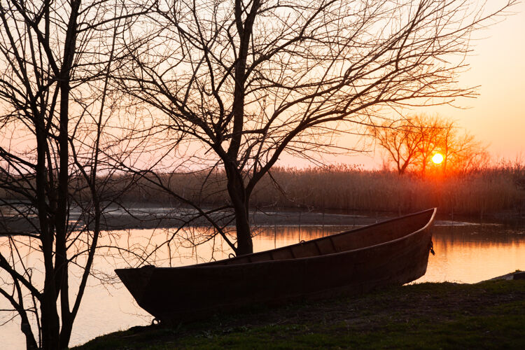 云宁静的春日夕阳伴着湖面上的小船 绿树和白雪水黄昏户外