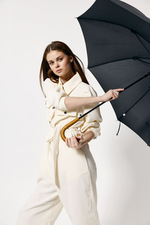 欢呼穿着白色西装的美女 带着开放式雨伞 现代风格的隔离墙成人快乐女士