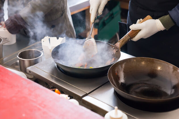 食物厨师或厨师在商业厨房的热盘子上煎炸 大煎锅上方有一团蒸汽薯条大型