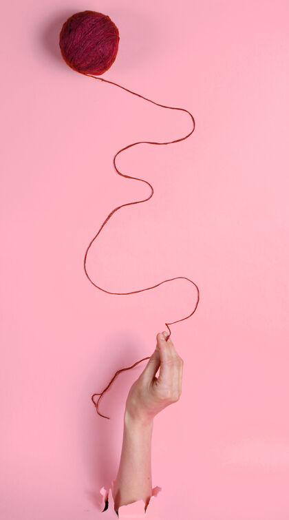 针女性的手拿着线穿过撕裂的粉红色纸简约创新医学理念线温暖符号