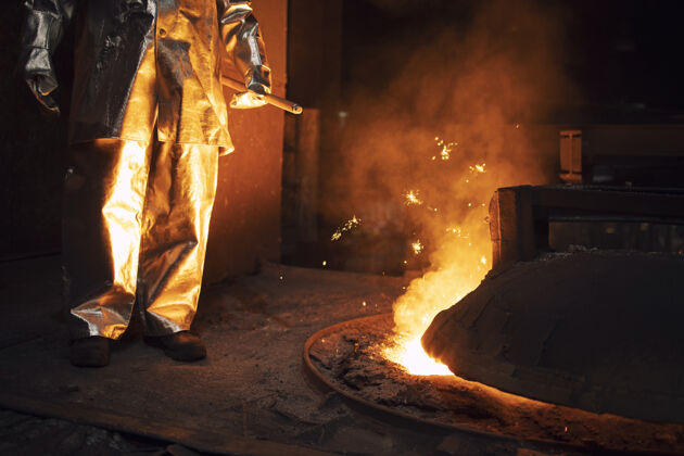 桶穿防护服的工人控制炉内炼铁 加热矿石提取贱金属热量创始人铸造