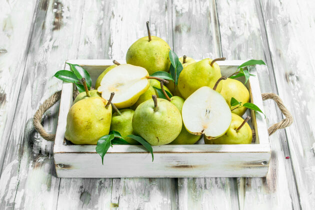 成熟新鲜的梨子和叶子放在木桌上的托盘上饮食树叶完美