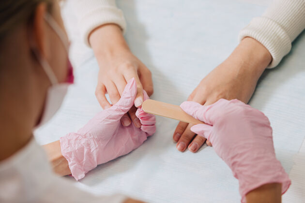 美容师修指甲的过程一个戴着粉色橡胶手套的师傅用指甲来修指甲文件.female把手收起来工具指甲油工艺