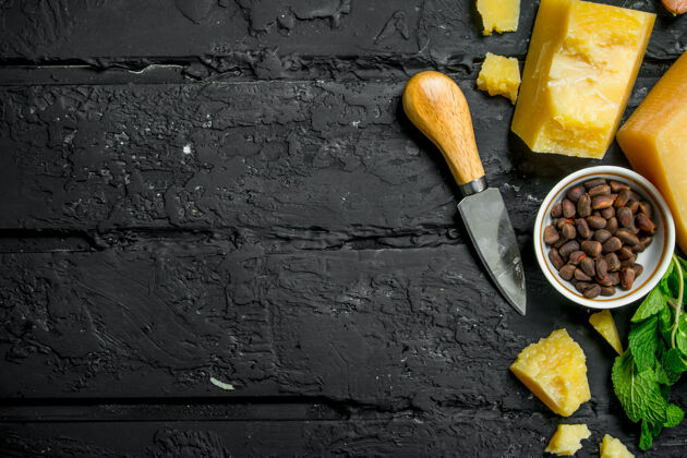 切割帕尔玛干酪配大蒜 松子和薄荷叶放在黑色乡村餐桌上餐桌开胃菜顶部