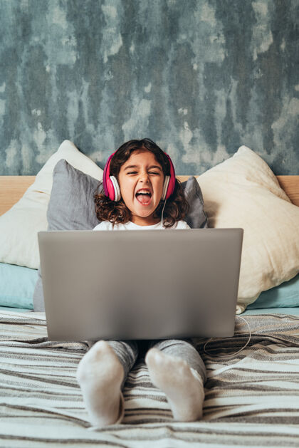 电信小女孩拿着电脑在床上笑享受房间互联网