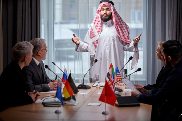 员工阿拉伯酋长举行了一次没有联系的会议 讨论议程上的想法和问题 并用麦克风给予支持语音输入会议室里 多民族的同事聚在一起商务人士混合房间