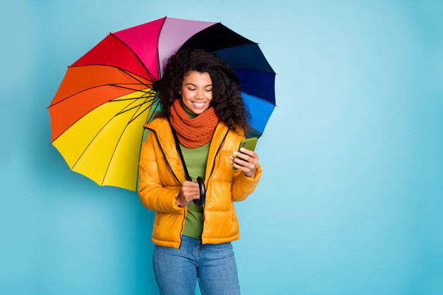 年轻深色皮肤的女士用阳伞在蓝色背景上打电话女孩多民族非洲