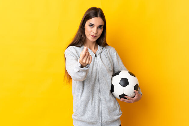 年轻年轻的足球运动员女人孤立在黄色背景赚钱的姿态经济游戏经济
