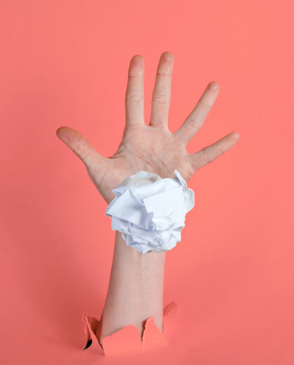 垃圾女人的手把揉成团的纸团扔进撕破的粉色纸里背景：极简主义理念创意揉皱文件