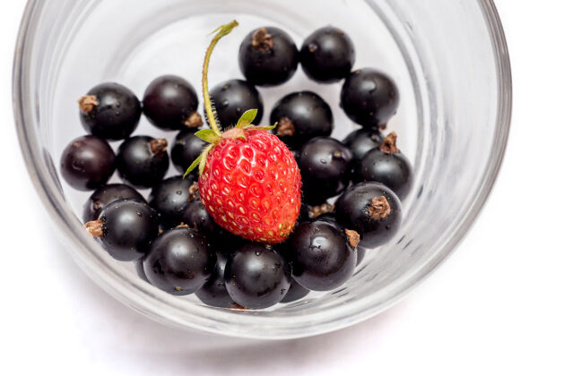 美食葡萄干和草莓在一个白色的孤立背景玻璃杯特写饮食浆果吃