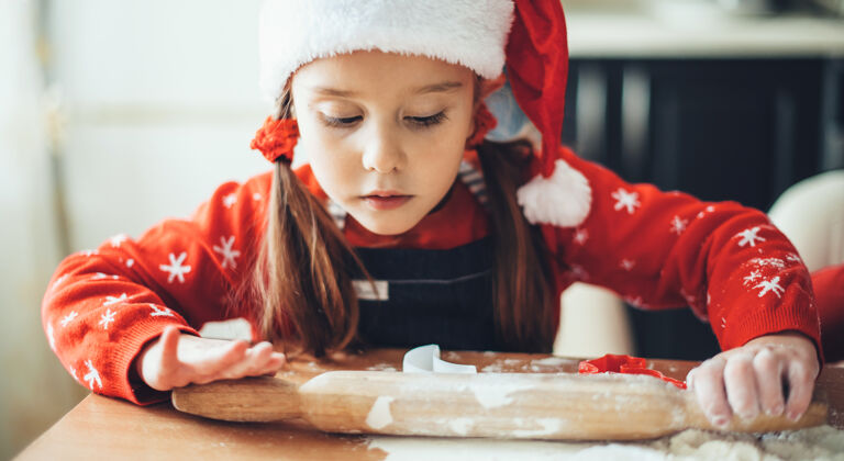 帽子一个白人女孩穿着圣诞老人的衣服在家里准备圣诞节 正在擀面团爱厨房降临