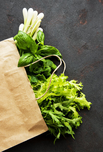 食品在一张黑桌子上的纸袋里放着新鲜的绿色蔬菜健康薄荷生的