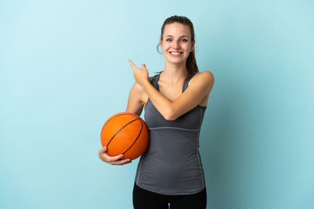 爱好打篮球的年轻女子孤零零地指着蓝色背景边上的一款产品运动比赛右
