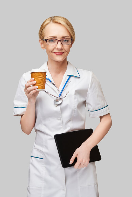 电脑一位女医生拿着一杯纸咖啡 拿着平板电脑的照片杯子女性外卖