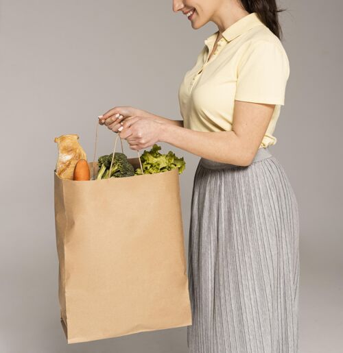 女人拿着蔬菜纸袋的女人靠近点零浪费女人花椰菜