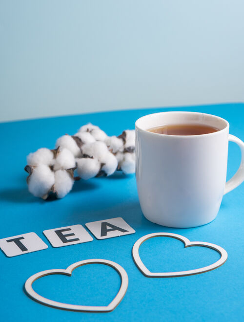 草药选择性聚焦：蓝色平原上的白色杯子里放着锡兰红茶 复制空间.硬纸板英文单词tea中的字母传统早餐茶