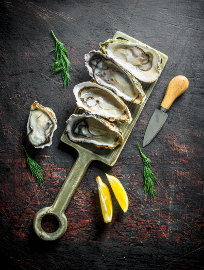 美味新鲜牡蛎放在砧板上 柠檬片放在深色木桌上海洋刀海洋