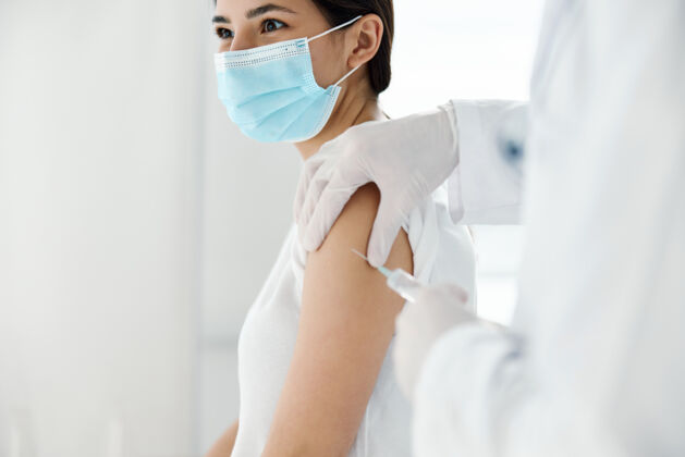 冠状病毒戴着防护手套的医生将疫苗注射到一名女性患者的肩膀上 进行疫苗接种防护妇女室内